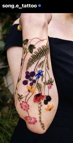 a woman's arm with flowers and leaves painted on it