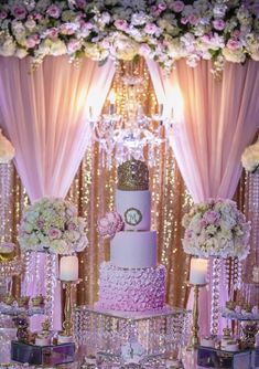 a table topped with a pink cake and lots of white flowers on top of it