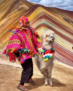 a man in colorful clothing standing next to a llama