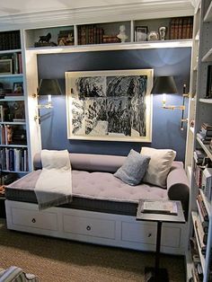 a living room filled with furniture and bookshelves next to a painting on the wall