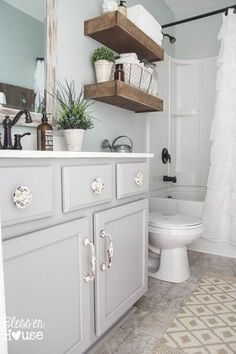 a white toilet sitting in a bathroom next to a sink and bathtub with shelves above it