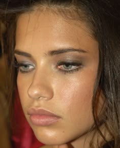 a close up of a young woman with long hair and blue eyes wearing a red dress