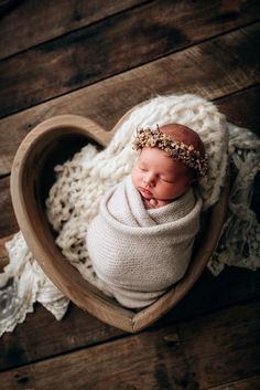 a newborn baby is wrapped in a heart - shaped blanket and wearing a headband