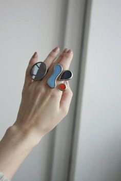 a woman's hand holding two rings with different shapes and colors on each one