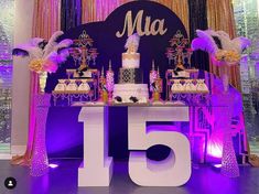 a table topped with a cake and lots of desserts next to a purple backdrop