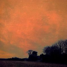 an orange sky with trees in the foreground and brown grass on the far side