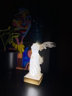 a white statue sitting on top of a wooden table next to a potted plant