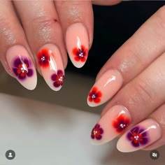 a woman's nails with red and purple flowers painted on the tip of them