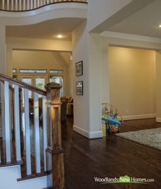 an empty living room with stairs leading up to the second floor and children's play area