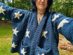 a woman wearing a blue crocheted sweater with white stars on it and her arms stretched out