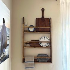 a wooden shelf with plates and utensils hanging on it's side wall