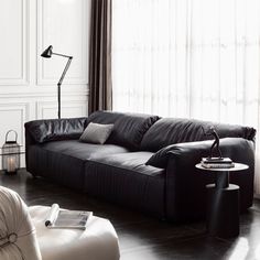 a living room with black leather furniture and white walls