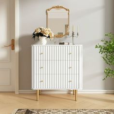 a white dresser with flowers on top and a mirror in the corner next to it