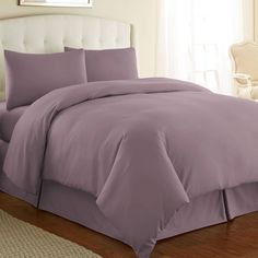 a bed with purple sheets and pillows in a room