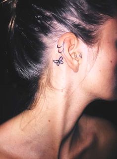 a woman's ear has a butterfly tattoo on it