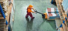 a man in an orange hat is using a hand pusher to move pallets