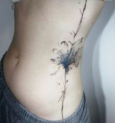 a woman's stomach with a flower tattoo on her side and the bottom part of her belly