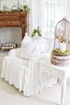 a birdcage sitting on top of a white couch in a living room next to a fireplace