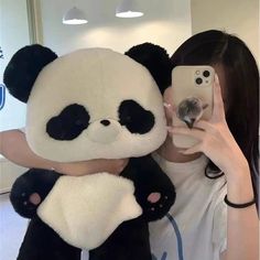 a woman taking a selfie with a giant stuffed panda bear