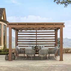 an outdoor dining table and chairs under a wooden pergolan structure with mountains in the background