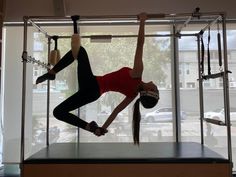 two women doing acrobatic exercises in front of a window