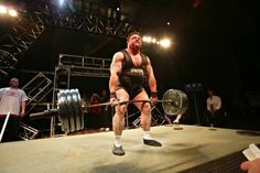 a man holding a barbell on top of a stage