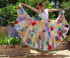 a woman in a white top is holding up a colorful piece of cloth that has been made into a skirt