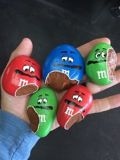 four rocks with faces painted on them in the shape of m & m's