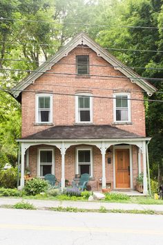 an old brick house with two porches on the front and second story is surrounded by trees