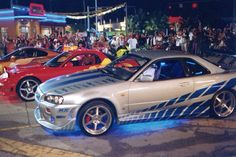 several cars parked on the street with people watching them