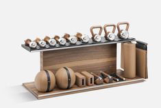 an assortment of different types of kettles and exercise balls on a wooden stand with metal handles