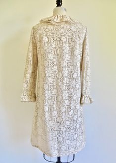 "The 1960's saw a revolution in what women chose to wear. No longer was there a need for girdles to cinch the waist but rather a \"Youth Quake\" (think Mary Quant) took place that saw the introduction of mini skirts and A line silhouettes. This fantastic 60's dress is made in a creme/ivory cotton lace that is finely crocheted (by machine). Highest quality construction. A-line silhouette with a ruffle at the round neckline and at the center front opening that is made up of a layer of lace and a l Beige Ruffled Vintage Dress For Wedding, Cream Lace Vintage Dress With Ruffles, Cream Vintage Dress With Ruffles For Formal Occasions, Cream Vintage Dress With Ruffles For Wedding, Classic Cream Dress For Vintage Events, Cream Vintage Wedding Dress With Ruffles, Regency Style Ruffled Vintage Dress For Wedding, Fitted Cream Vintage Dress For Vintage Style Events, Retro Vintage Lace Dress For Daywear