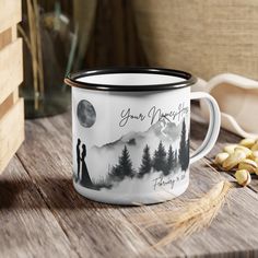 a white and black coffee mug sitting on top of a wooden table next to peanuts