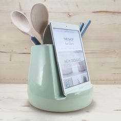 a cell phone is sitting in a cup with spoons and utensils inside