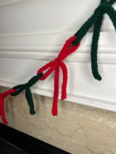 two red and green knitted christmas garlands hanging from the side of a fireplace