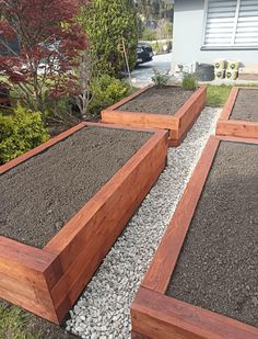 several wooden planters filled with gravel in front of a house