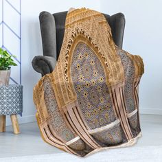 a chair with a blanket on it sitting in front of a potted plant