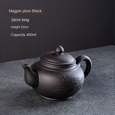 a black teapot sitting on top of a table next to a gray countertop