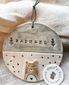 a ceramic ornament with a bear in the center and name raphael on it