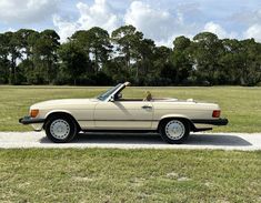 a beige convertible car parked on the side of a road