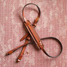 a pair of brown leather straps laying on top of a red and white fabric covered surface