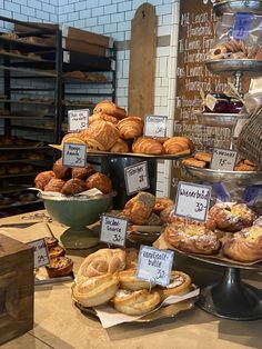 breads and pastries are on display in a bakery shop, with price signs