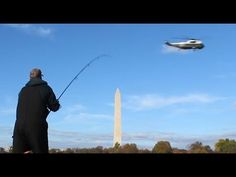 a man is fishing in front of the washington monument with a helicopter flying above him