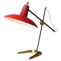 a red and gold desk lamp on a white background