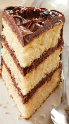 a piece of cake with chocolate frosting and sprinkles on it next to a fork