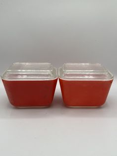 two red glass containers sitting on top of a white table