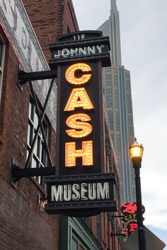 the neon sign for johnny cash's museum is lit up in front of an old brick building