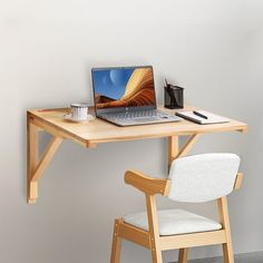 a laptop computer sitting on top of a wooden desk next to a cup of coffee