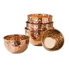 four copper bowls are stacked on top of each other