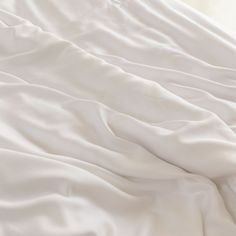 an unmade bed with white sheets and pillows